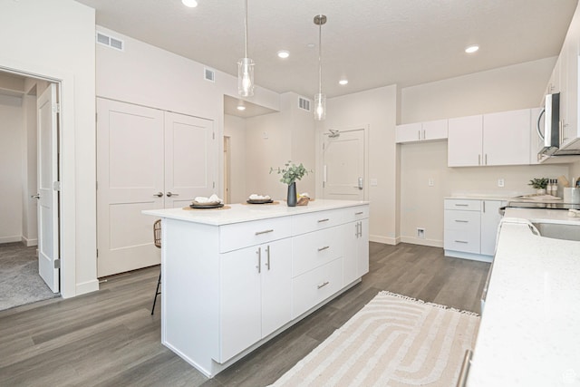 kitchen featuring hanging light fixtures, white cabinets, dark hardwood / wood-style floors, and a center island