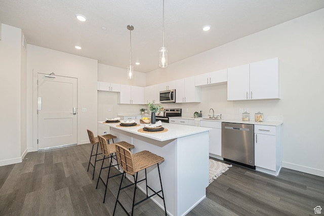 kitchen featuring hanging light fixtures, appliances with stainless steel finishes, white cabinets, and a kitchen island