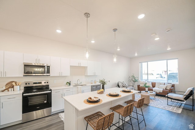 kitchen featuring sink, hanging light fixtures, white cabinets, and stainless steel appliances