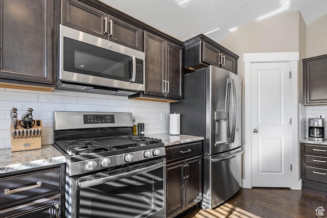 kitchen with light stone counters, dark brown cabinetry, stainless steel appliances, and dark wood-type flooring