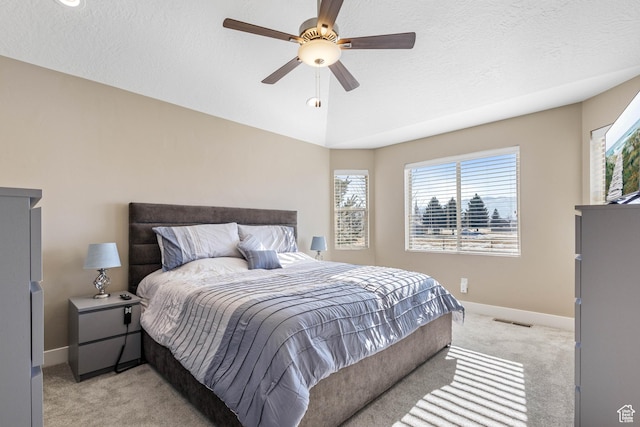 bedroom featuring visible vents, a ceiling fan, baseboards, a textured ceiling, and light colored carpet