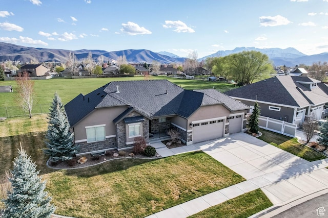 view of front facade featuring a garage, stone siding, fence, and a mountain view