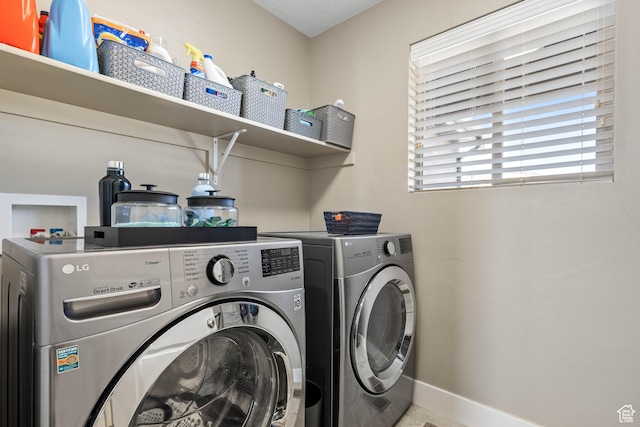 clothes washing area with washing machine and clothes dryer, laundry area, and baseboards
