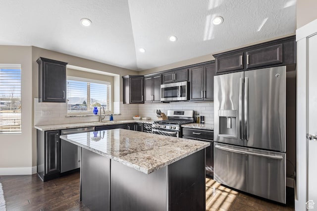 kitchen with a sink, decorative backsplash, stainless steel appliances, dark wood-type flooring, and a kitchen island