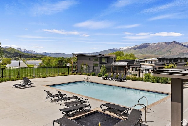 community pool featuring fence, a patio area, and a mountain view