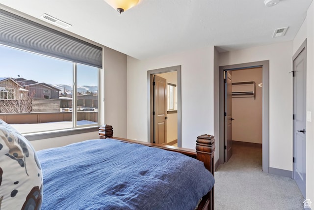 bedroom with a walk in closet, a wall mounted air conditioner, visible vents, and carpet floors