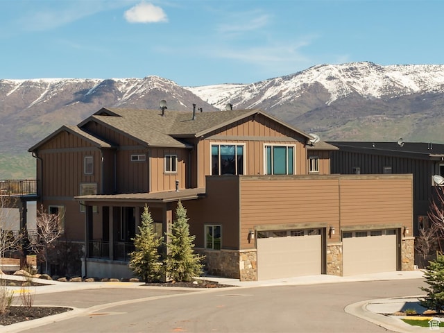 craftsman house with a mountain view, stone siding, a garage, board and batten siding, and driveway