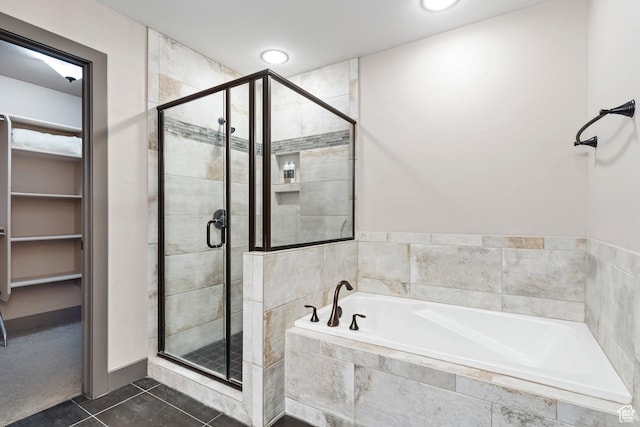 bathroom featuring a bath, a stall shower, a spacious closet, and tile patterned floors