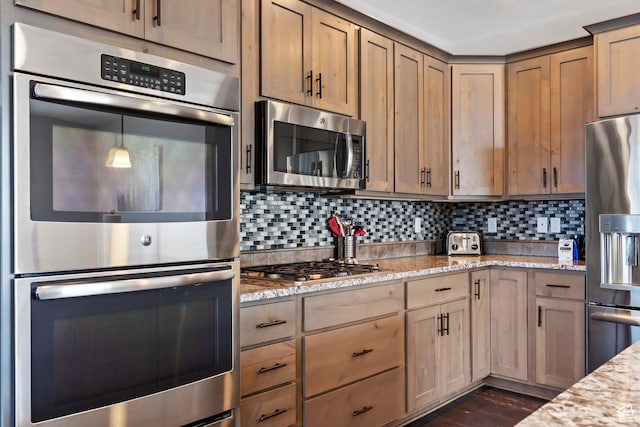 kitchen with stainless steel appliances, tasteful backsplash, and light stone counters