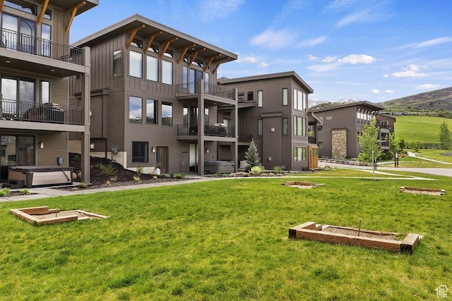 view of community with a jacuzzi, a mountain view, and a lawn