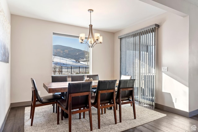 dining space with baseboards, an inviting chandelier, and wood finished floors