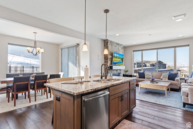 kitchen with light stone countertops, dishwasher, a sink, open floor plan, and dark wood-style floors