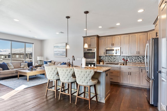 kitchen featuring open floor plan, light stone counters, dark wood finished floors, and stainless steel appliances