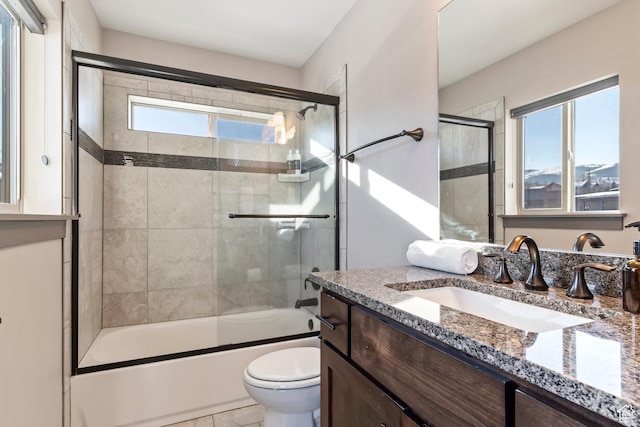full bath with vanity, toilet, combined bath / shower with glass door, and a healthy amount of sunlight