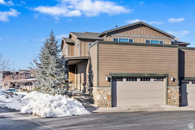 view of front of property featuring board and batten siding, stone siding, and a garage