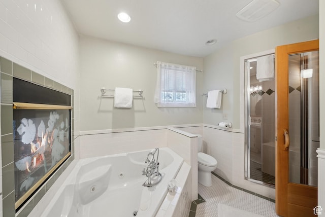 bathroom with tile patterned flooring, tile walls, plus walk in shower, and toilet