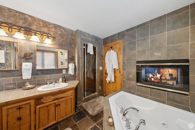 bathroom featuring tile walls, vanity, shower with separate bathtub, and a multi sided fireplace