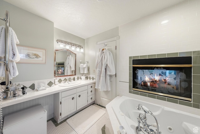bathroom with a bathtub, a multi sided fireplace, vanity, a textured ceiling, and tile patterned floors