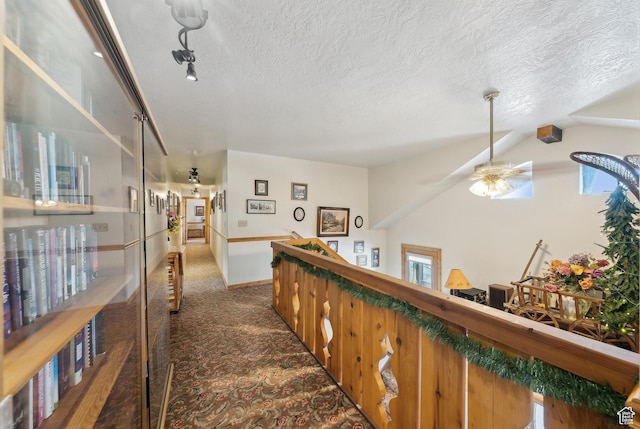 hallway with vaulted ceiling, a textured ceiling, and dark carpet
