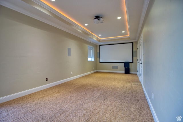 home theater with crown molding, light colored carpet, and a tray ceiling