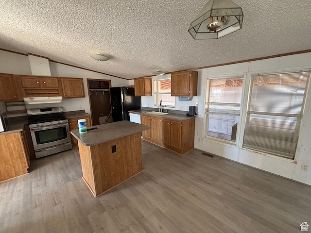 kitchen with a center island, gas stove, black refrigerator, sink, and light wood-type flooring