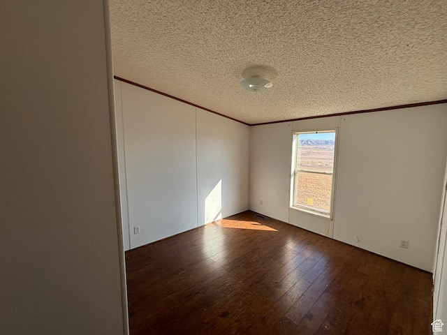 spare room with a textured ceiling and dark hardwood / wood-style floors