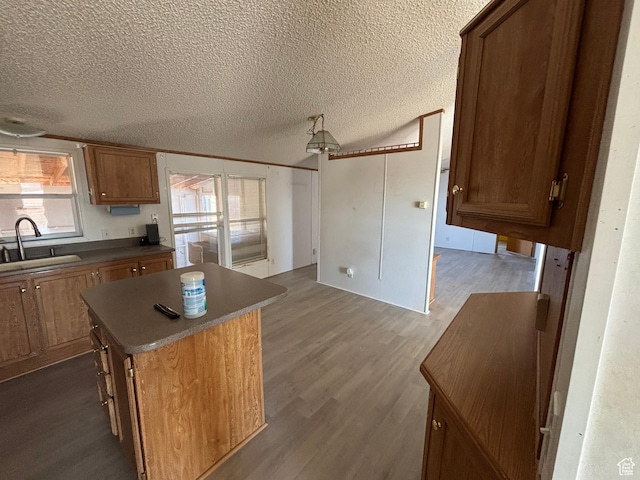 kitchen with dark wood-type flooring, sink, a textured ceiling, and a center island
