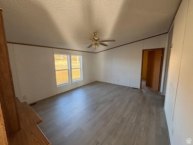 empty room featuring light hardwood / wood-style floors, a textured ceiling, ornamental molding, and ceiling fan