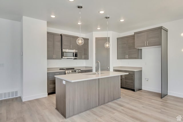 kitchen with a sink, stainless steel appliances, light countertops, baseboards, and visible vents