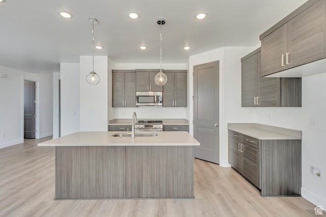 kitchen featuring stainless steel appliances, a sink, baseboards, light wood-style floors, and light countertops