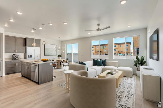 living room with recessed lighting, light wood-type flooring, and ceiling fan with notable chandelier