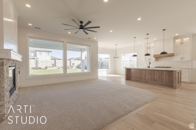 3783 S Kennedy Ln, Washington, UT 84780 - unfurnished living room featuring light wood-type flooring, ceiling fan with notable chandelier, and a stone fireplace