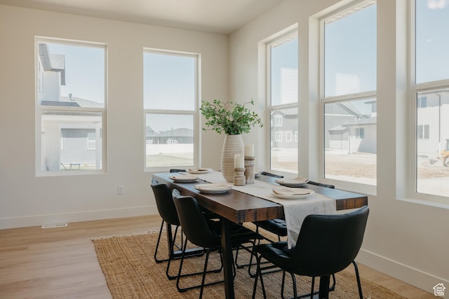 dining room with light wood-type flooring, plenty of natural light, and baseboards