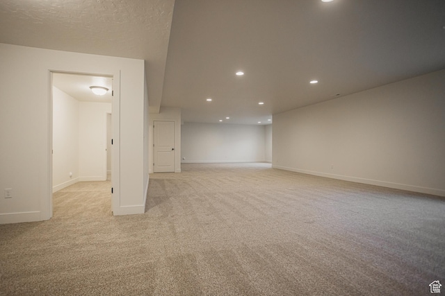 basement with baseboards, light carpet, and recessed lighting