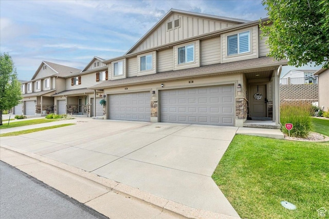 1841 E Whitetail Dr, Layton, UT 84040 - townhome / multi-family property featuring board and batten siding, a garage, concrete driveway, a front yard, and stone siding