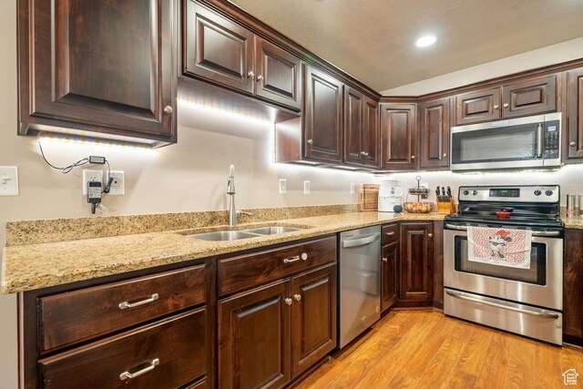 1841 E Whitetail Dr, Layton, UT 84040 - kitchen with appliances with stainless steel finishes, light wood-type flooring, dark brown cabinetry, a sink, and light stone countertops