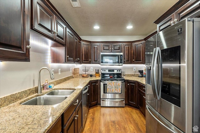 1841 E Whitetail Dr, Layton, UT 84040 - kitchen featuring appliances with stainless steel finishes, light wood-style floors, dark brown cabinetry, recessed lighting, and light stone countertops
