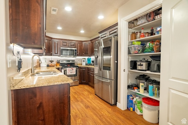 1841 E Whitetail Dr, Layton, UT 84040 - kitchen with stainless steel appliances, a sink, light stone countertops, light wood-type flooring, and dark brown cabinetry