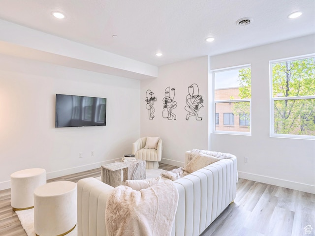 living room featuring baseboards, light wood-style flooring, visible vents, and recessed lighting