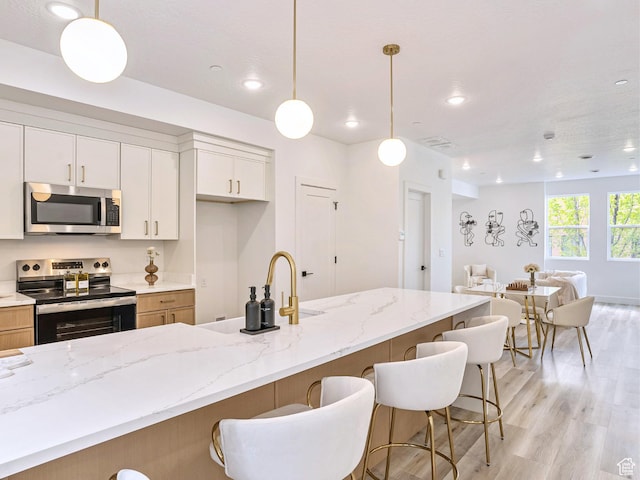 kitchen featuring light wood-type flooring, a kitchen breakfast bar, open floor plan, and stainless steel appliances