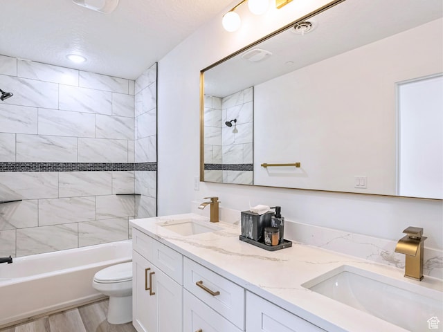 full bath with double vanity, toilet, a sink, shower / tub combination, and a textured ceiling