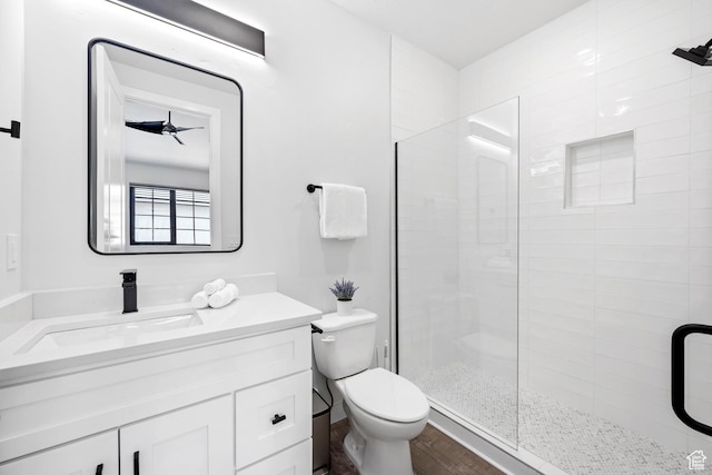 bathroom with toilet, a shower with shower door, ceiling fan, wood-type flooring, and vanity