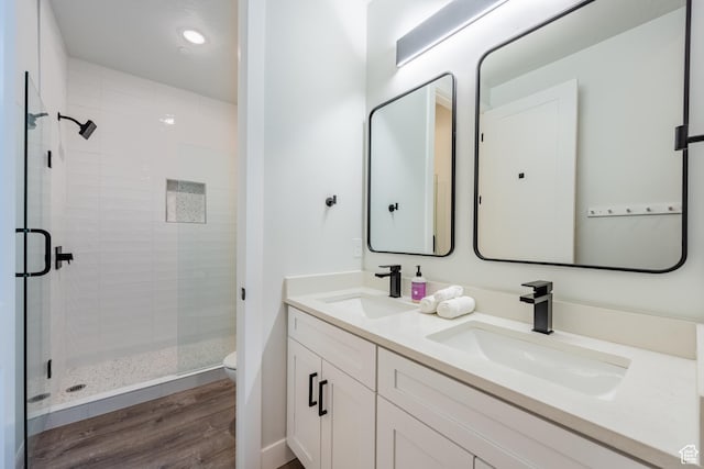 bathroom featuring hardwood / wood-style floors, walk in shower, vanity, and toilet