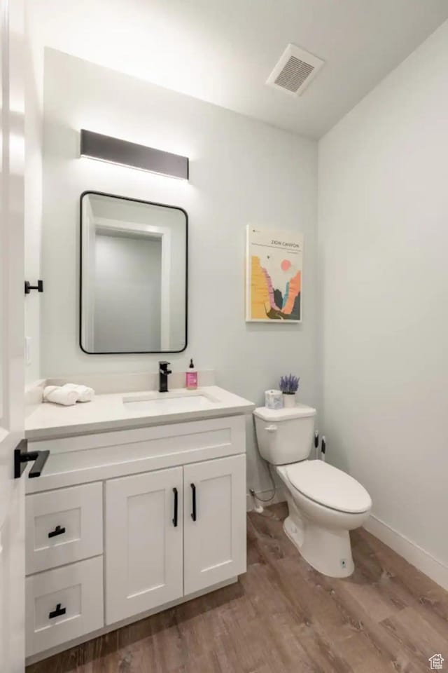 bathroom with hardwood / wood-style flooring, toilet, and vanity