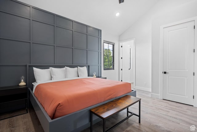 bedroom featuring light wood-type flooring and high vaulted ceiling