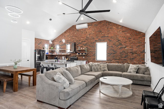 living room featuring ceiling fan, a wall mounted air conditioner, brick wall, and light hardwood / wood-style floors