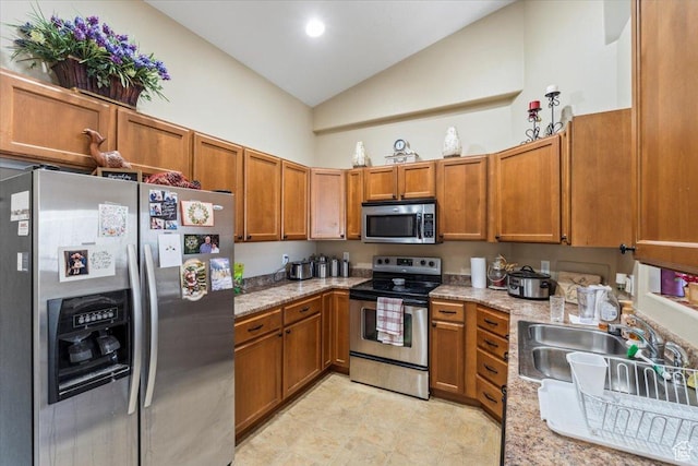 kitchen featuring light stone counters, sink, appliances with stainless steel finishes, and lofted ceiling