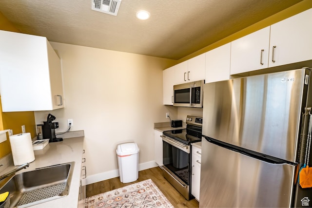 1283 N Gallen Rd W, Santa Clara, UT 84765 - kitchen with appliances with stainless steel finishes, sink, white cabinetry, and light hardwood / wood-style floors