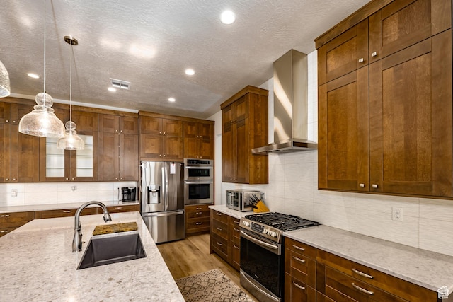 1283 N Gallen Rd W, Santa Clara, UT 84765 - kitchen featuring appliances with stainless steel finishes, wall chimney range hood, sink, hanging light fixtures, and light stone counters