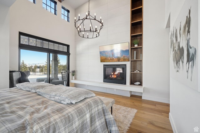 7242 Lupine Dr, Park City, UT 84098 - bedroom with a towering ceiling, a chandelier, baseboards, wood finished floors, and a tile fireplace